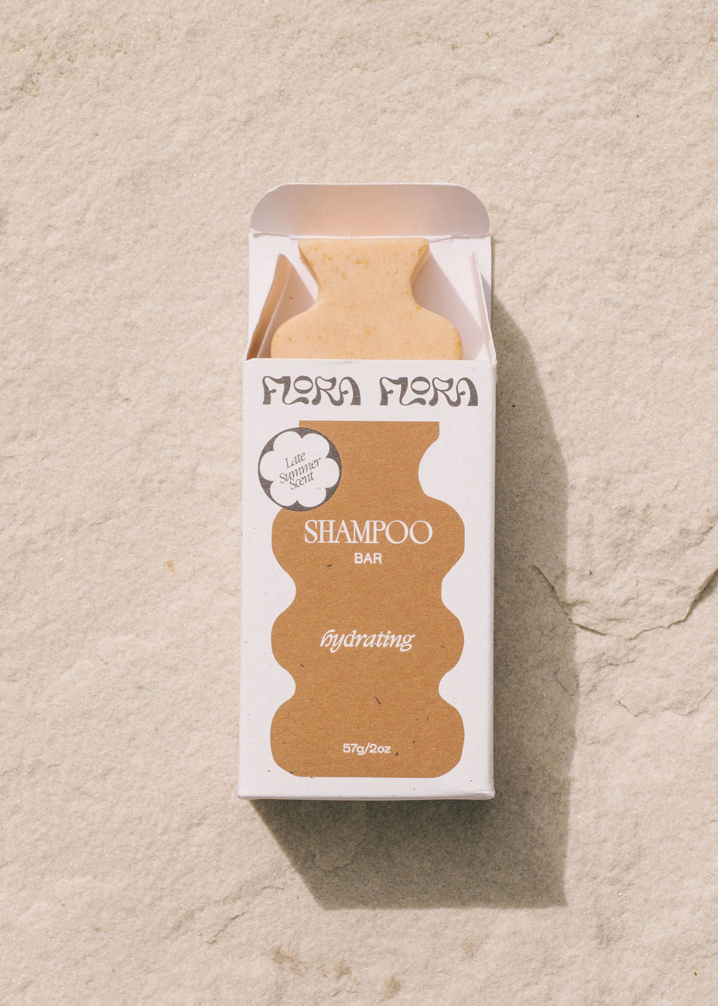 Flora Flora shampoo bar packaging on a beige stone surface