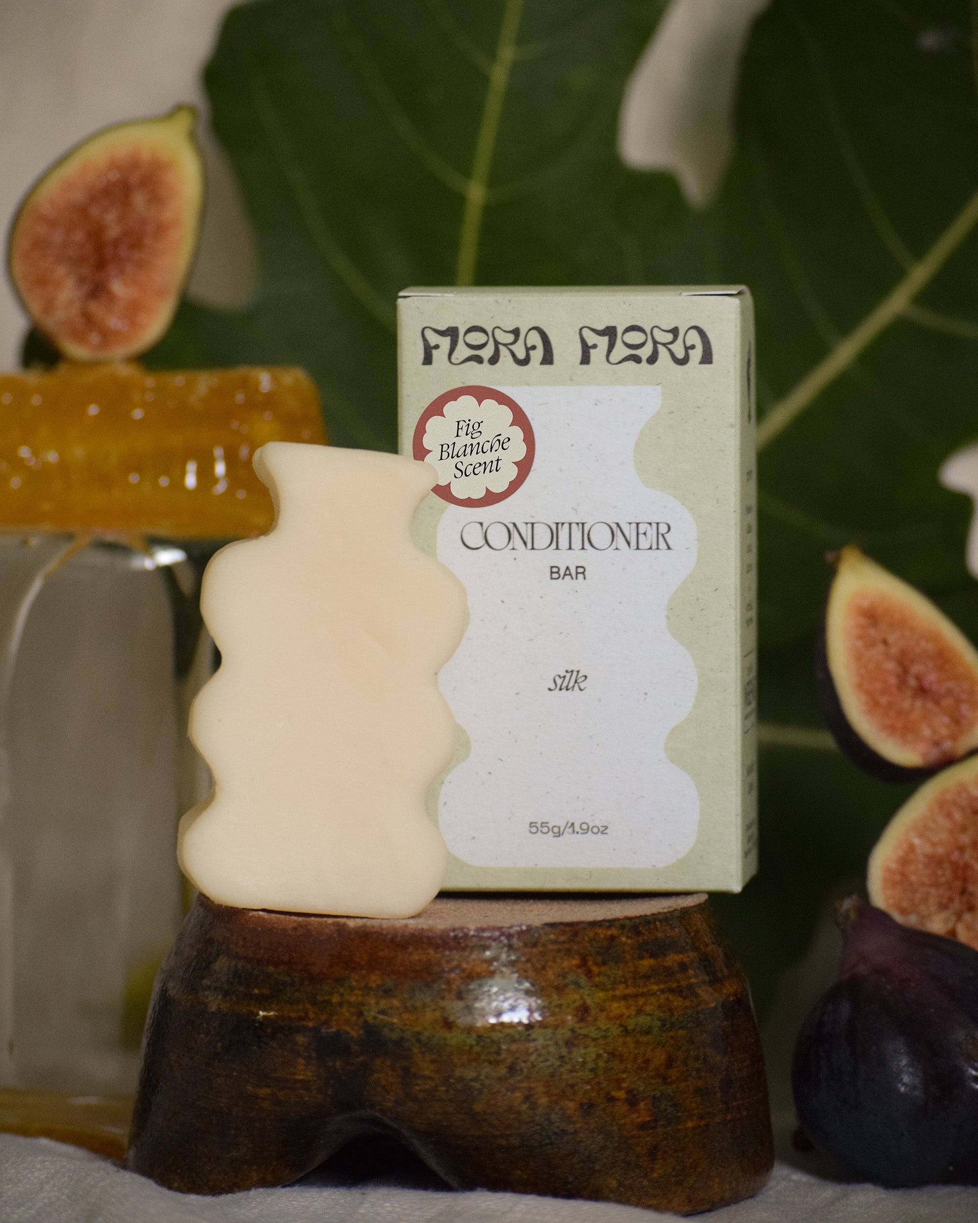Conditioner bar with packaging on a wooden stand, surrounded by figs and honey.