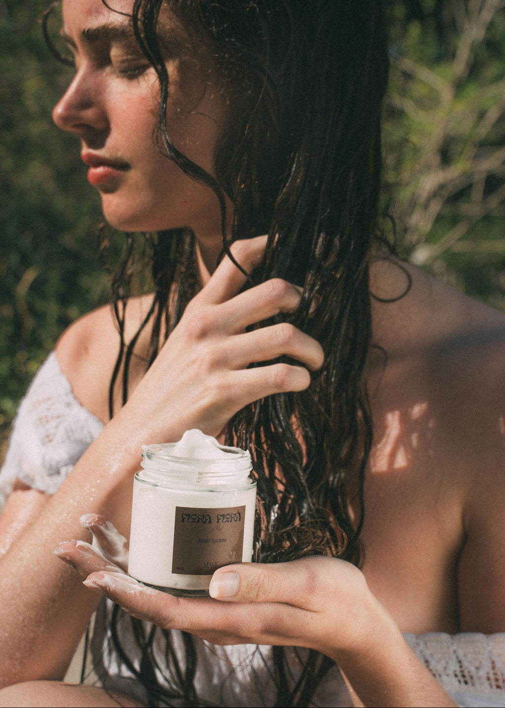 Woman applying a jar of root systems hair mask outdoors