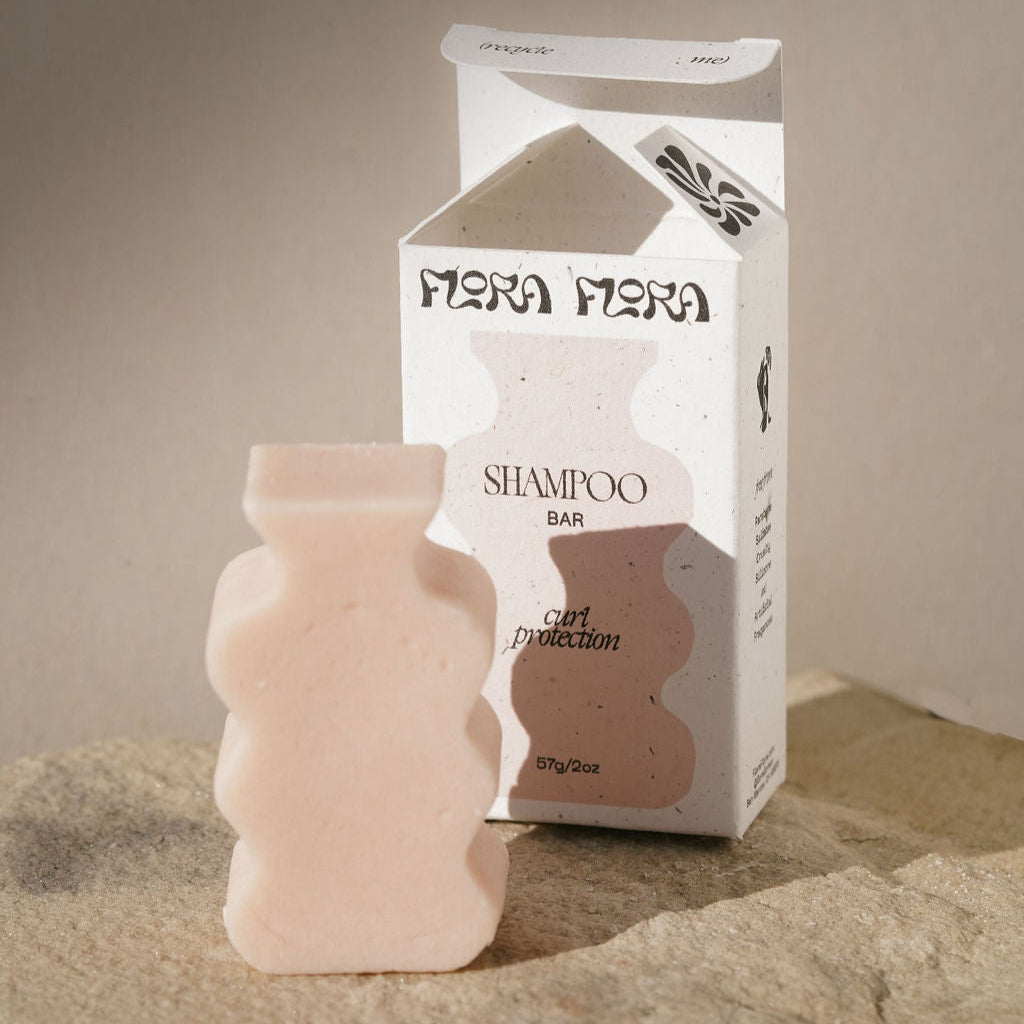 Flora Flora shampoo bar and packaging on a textured surface with a neutral background