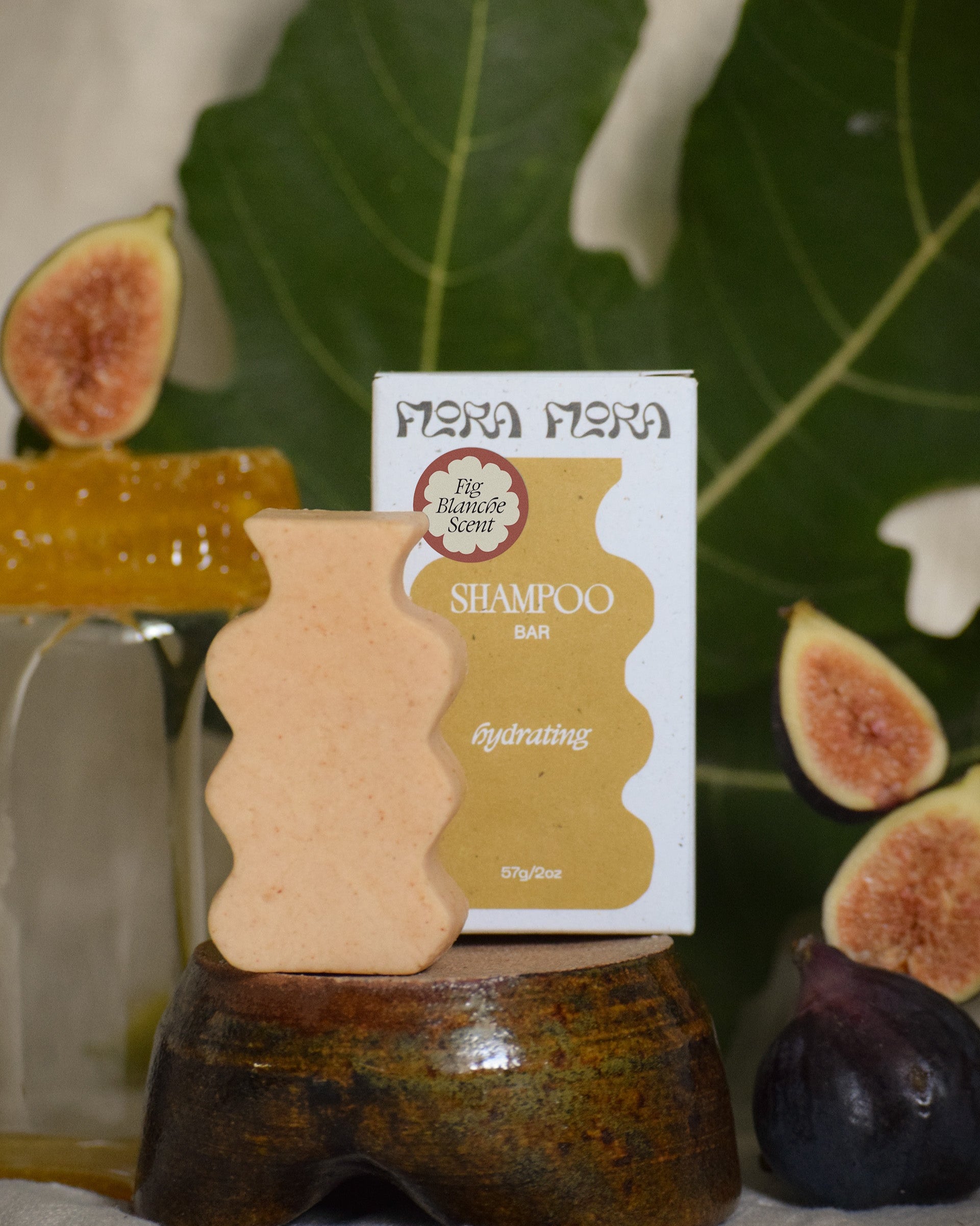 Shampoo bar with a label on a stand surrounded by figs, leaves, and honey