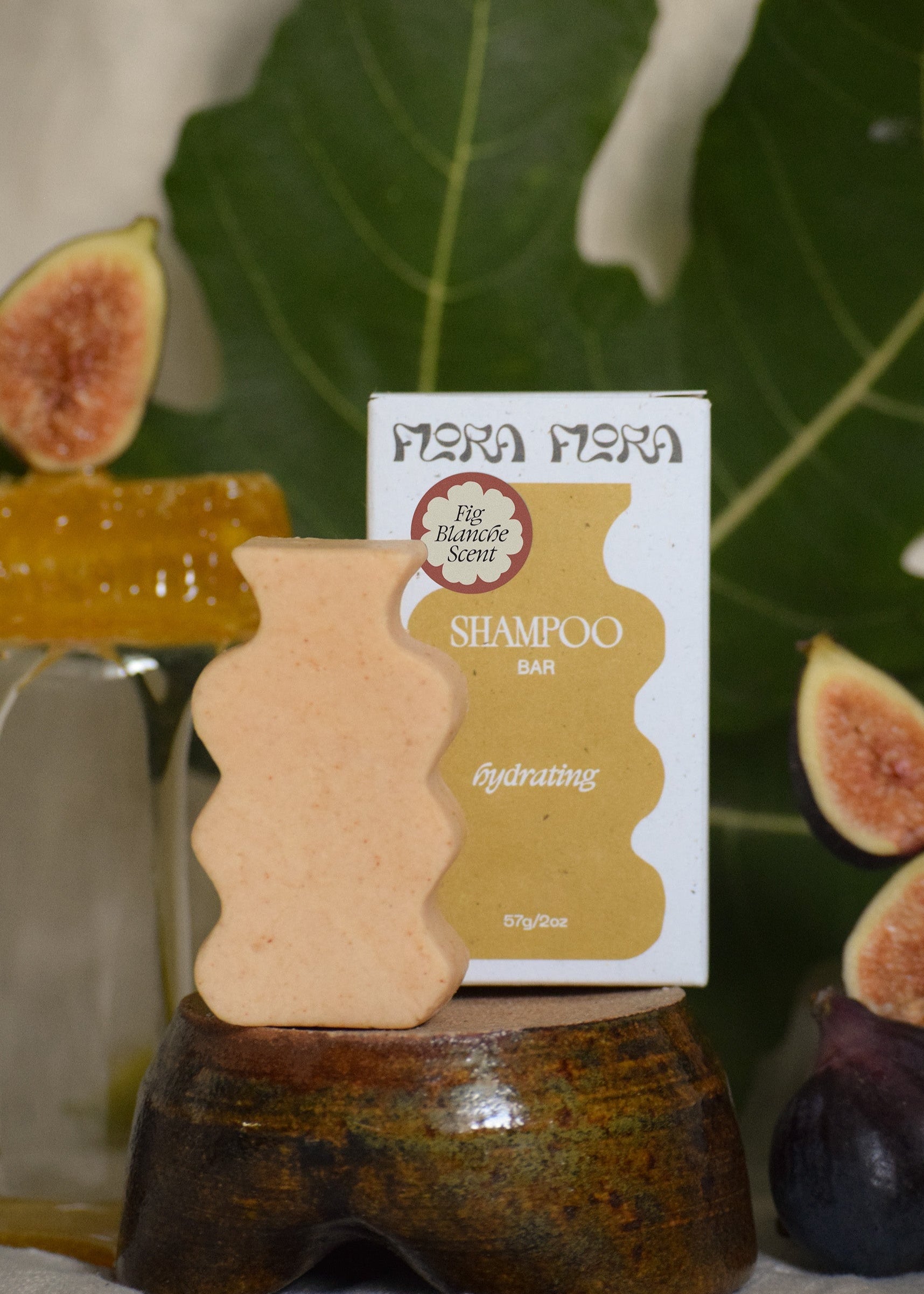 Shampoo bar with a label on a stand surrounded by figs, leaves, and honey
